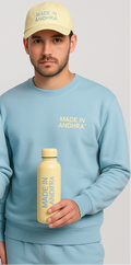 Two people wearing matching light blue outfits with 'MADE IN ANDhra' text, holding a yellow bottle.